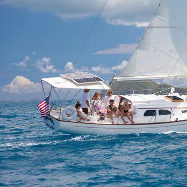 Group enjoying a sunny day on a sailboat in clear blue waters.
