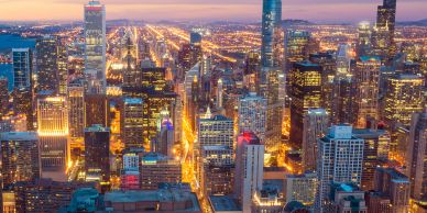 City skyline at dusk with illuminated streets and skyscrapers.