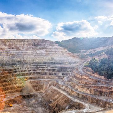 Large open-pit mine with terraced excavation under a partly cloudy sky.