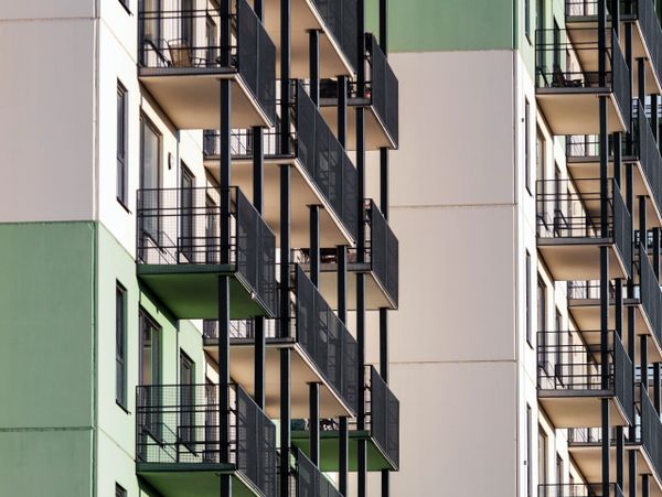 Modern apartment building with green and beige walls and black metal balconies.