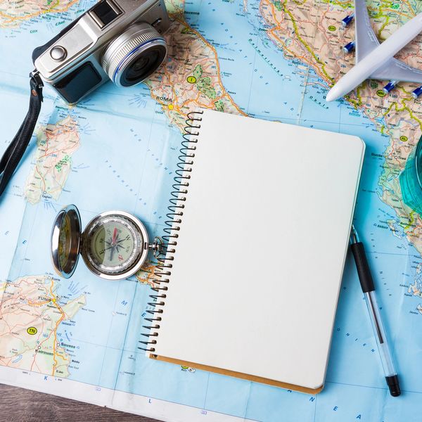 Map on table with notebook, compass, toy airplane, and camera