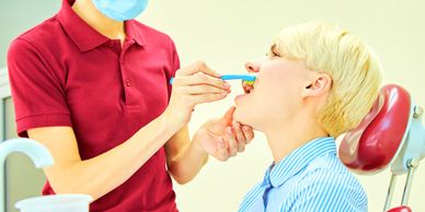 Dentist demonstrating proper toothbrushing to a patient in a dental clinic.