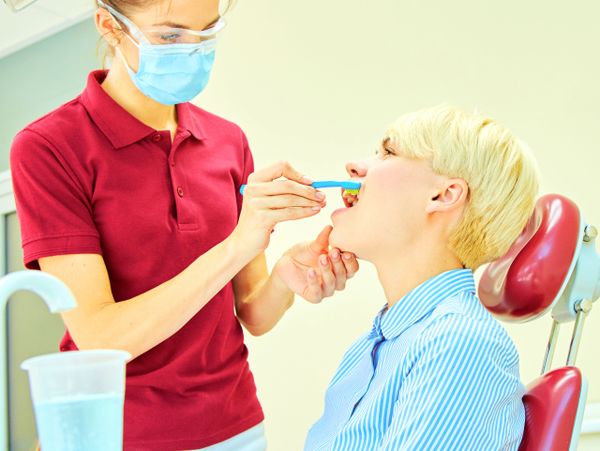 Dentist demonstrating proper toothbrushing to a patient in a dental clinic.