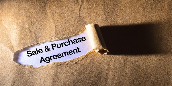 Torn paper revealing 'Sale &amp; Purchase Agreement' text.