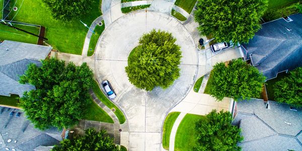 Aerial view of a suburban cul-de-sac with trees and parked cars.