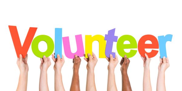 Hands hold colorful letters spelling 'Volunteer'.