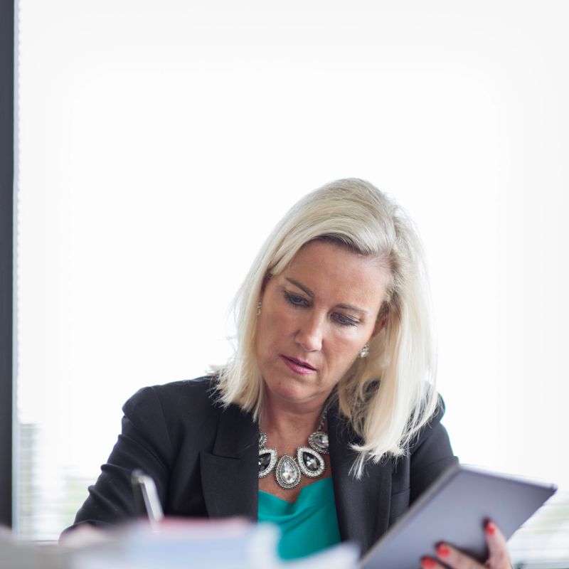 An attractive business woman working at a conference table using a tablet computer.