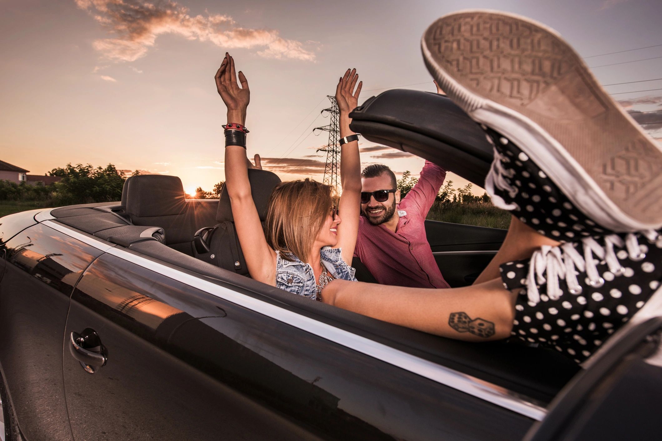 Couple enjoying a joyful ride in a convertible at sunset.