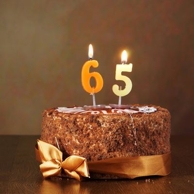 Chocolate birthday cake with lit 65 candles.