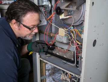 Technician inspecting the wiring inside a furnace unit.