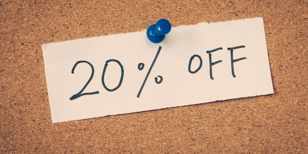 Handwritten 20% off sign pinned to corkboard with a blue thumbtack.