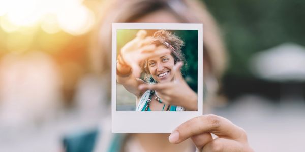 Person holding a Polaroid photo of a smiling woman.
