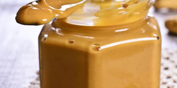 Close-up of creamy peanut butter in a jar with a spoon.