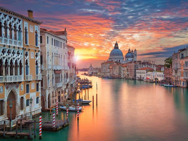 Sunset over Venice's Grand Canal with historic buildings and boats.
