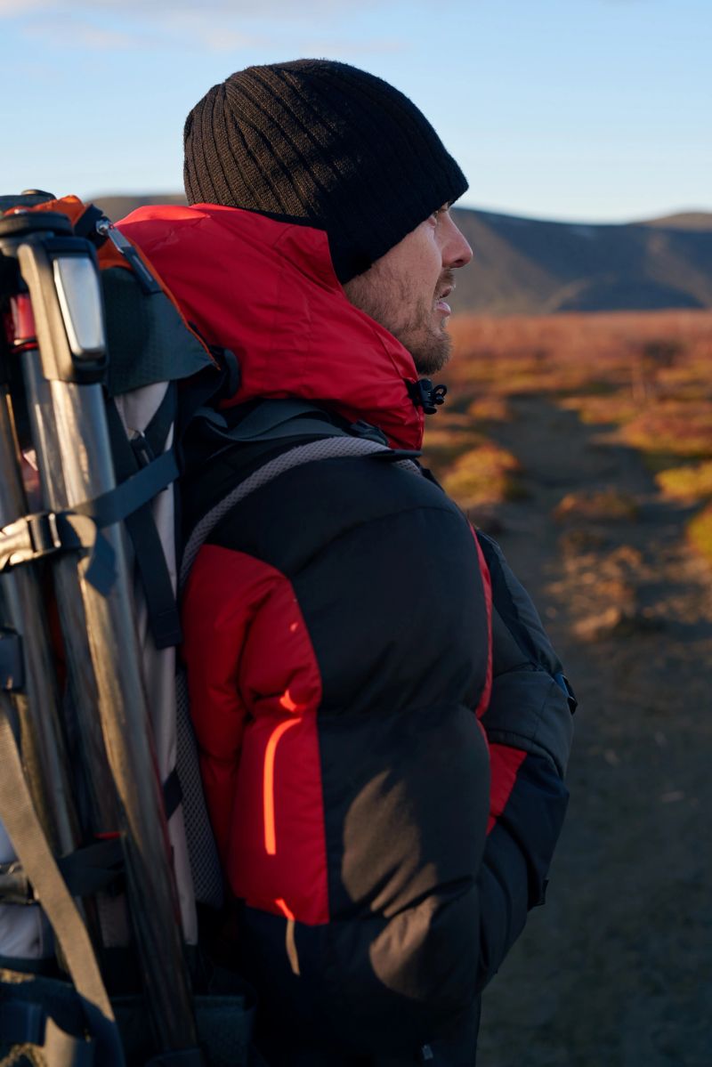 Hiking man outdoors with backpack and tripod to take nature landscape photographs