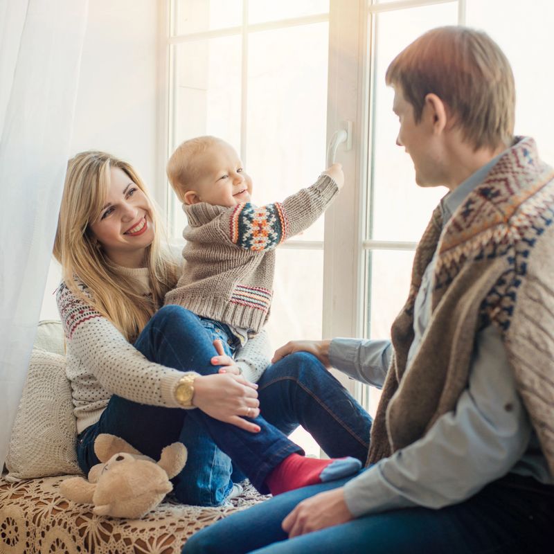 Happy family sitting on windowsill in front of window in winter.