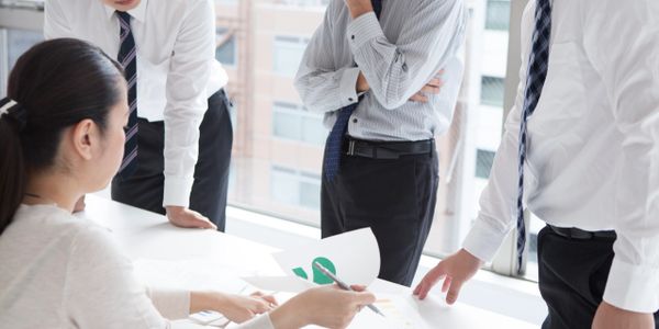 Four professionals in business attire discussing documents in a bright office.