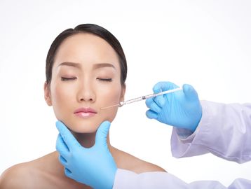 Woman receiving a cosmetic injection on her face.