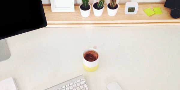Minimalistic desk setup with coffee and plants.