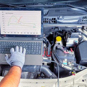 Technician diagnosing car engine performance with laptop.