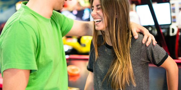Two young people share a happy moment at an arcade.