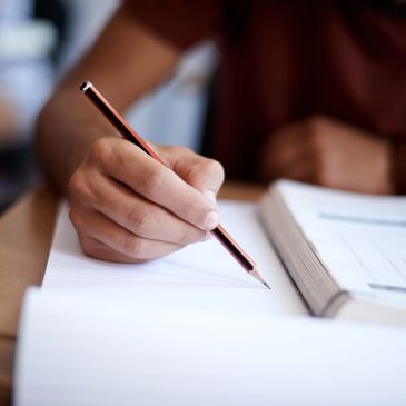 Person writing with a pencil on paper.