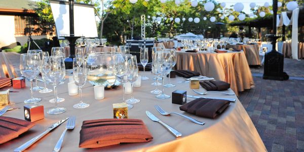 Elegant outdoor dining setup with round tables and glassware.