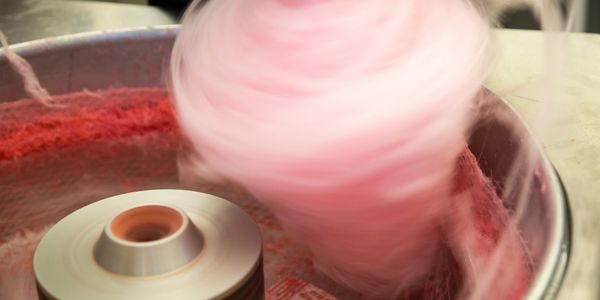 Close-up of pink cotton candy spinning on a machine.
