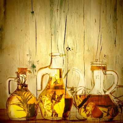 Vintage glass bottles with herbs inside on a rustic wooden background.