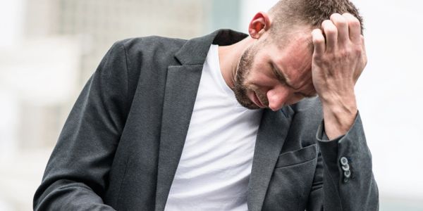 Man in a suit looking stressed and holding his head.
