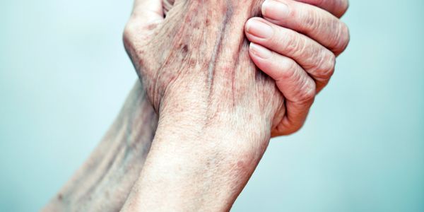 Two elderly hands clasped together showing care and support.