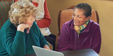 Two elderly women chat happily.