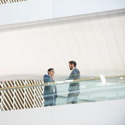 Two men in suits talking in a modern building.