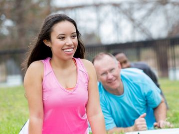 Young woman and others exercising outdoors.