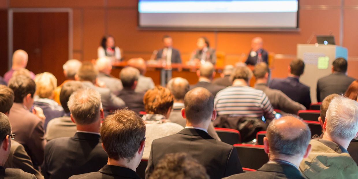 Audience attentively listening to a panel discussion in a conference room.