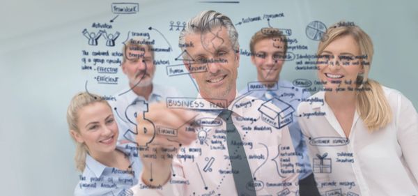 Businessman writing success-related words on transparent board.