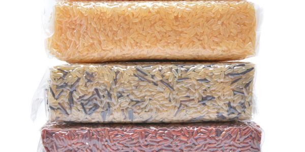 Four vacuum-sealed packs of different colored rice varieties stacked together.