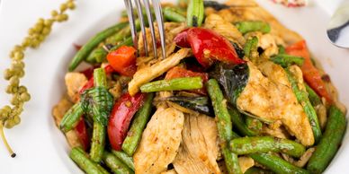 Stir-fried chicken with vegetables on a white plate.