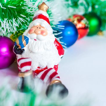 A playful Santa figurine with colorful ornaments and festive greenery.