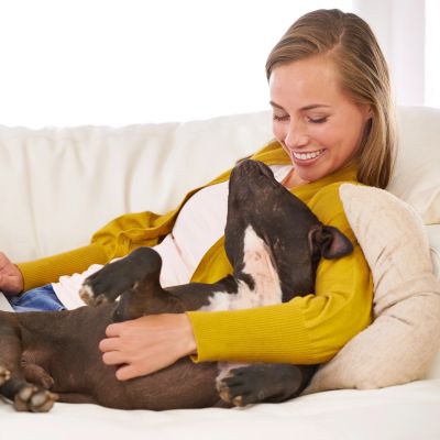 Woman smiling while cuddling her dog on a couch.