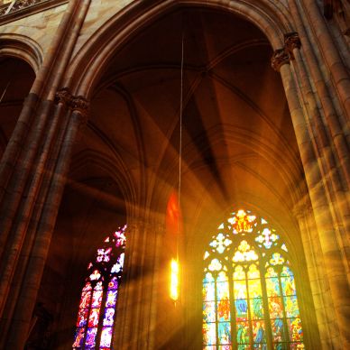 Sunlight streams through stained glass in a grand cathedral.