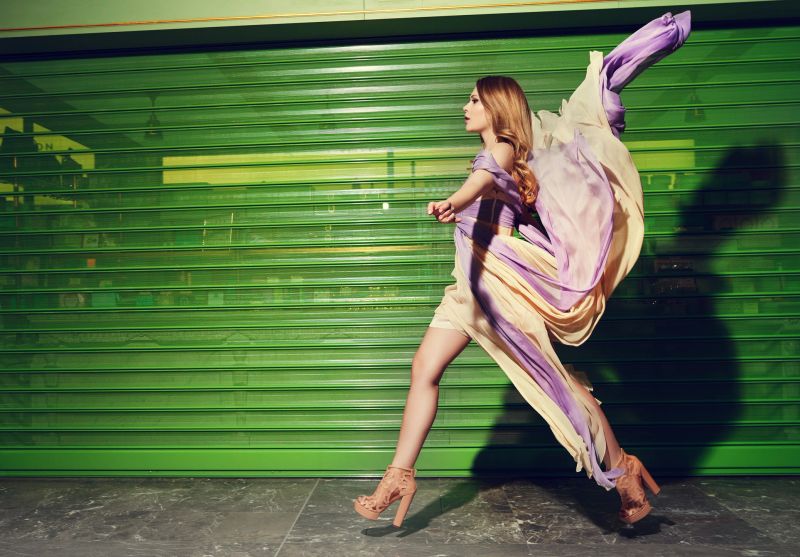 side view of fashionable woman on catwalk rushing, glamour dress in motion, seductive attitude.
