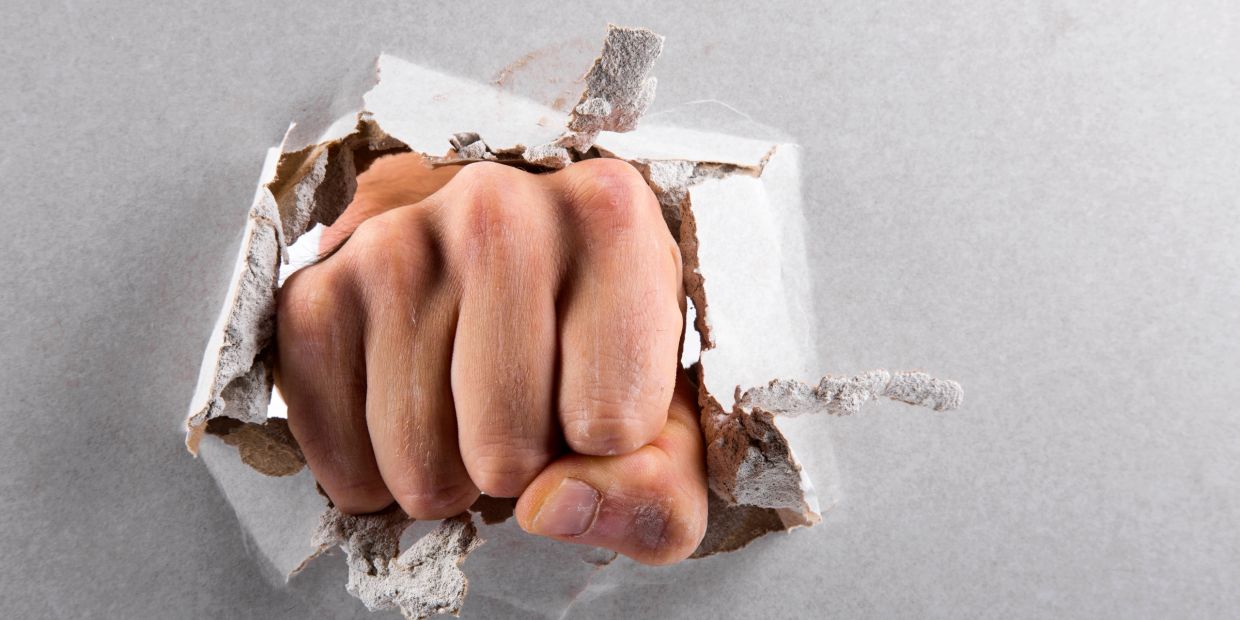 A fist breaking through damaged drywall representing professional fist-through-wall drywall repair s