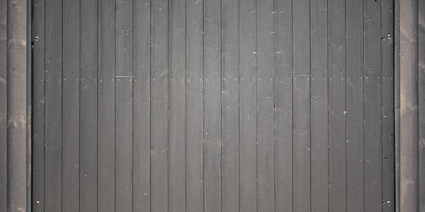 A dark gray wooden fence with vertical planks and a slightly weathered texture.