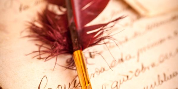 A vintage pen rests on a handwritten last will and testament document.