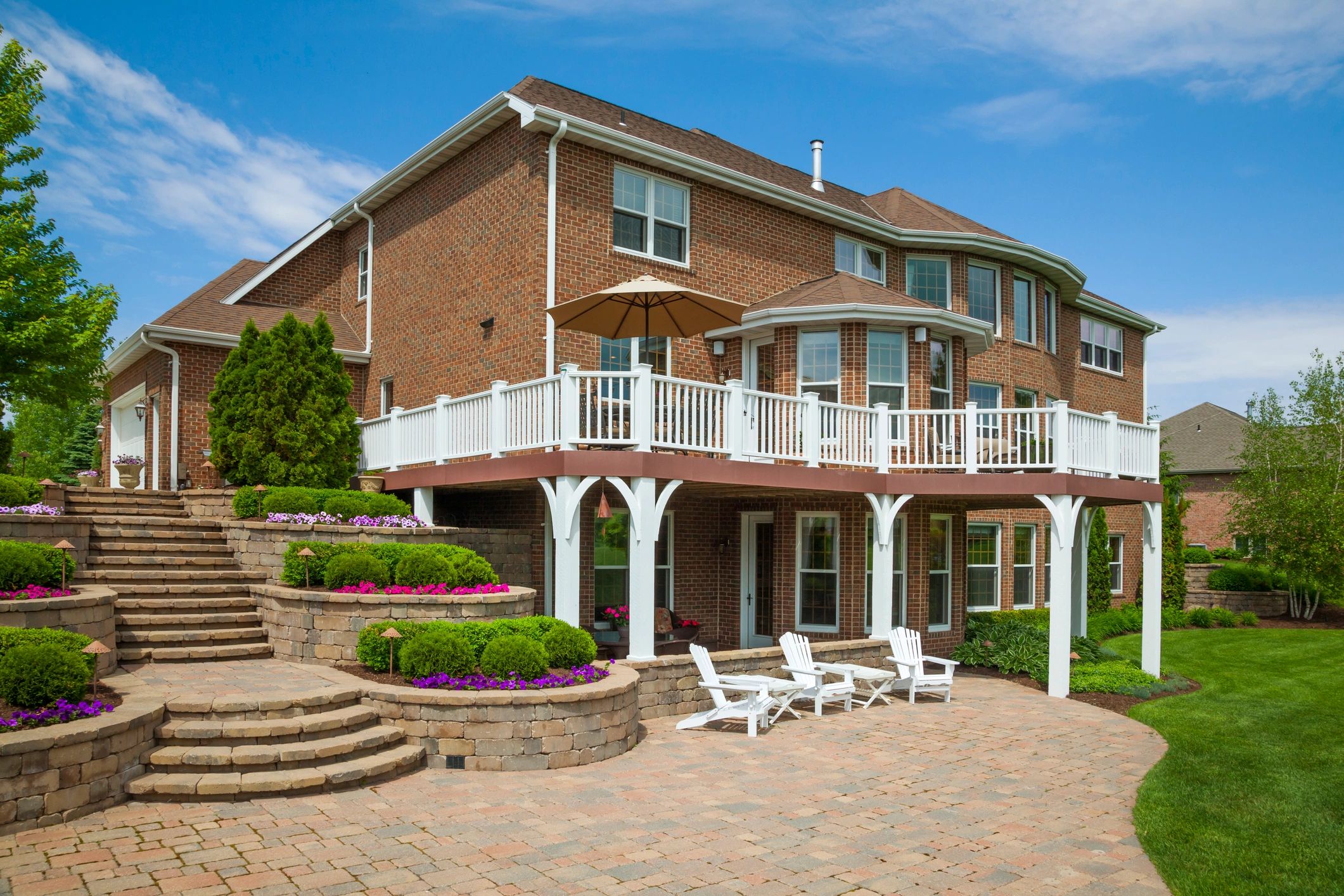 Large brick house with a spacious patio and landscaped garden.