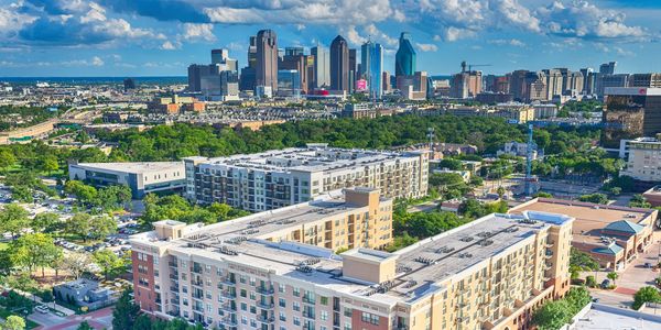 Aerial view of modern apartment buildings with a city skyline in the background.