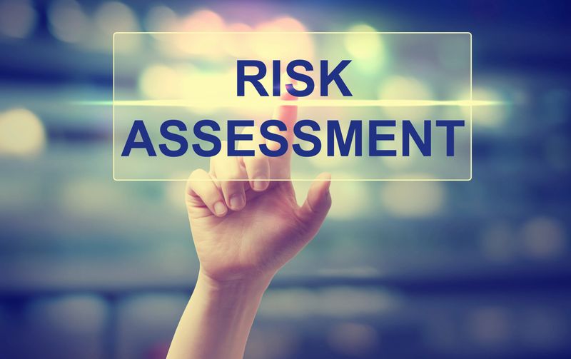 Hand pressing Risk Assesment on blurred cityscape background