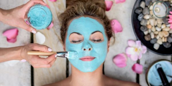 Woman receiving a blue facial mask treatment.