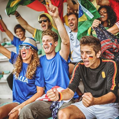 Excited fans cheering with face paint and flags at a sports event.